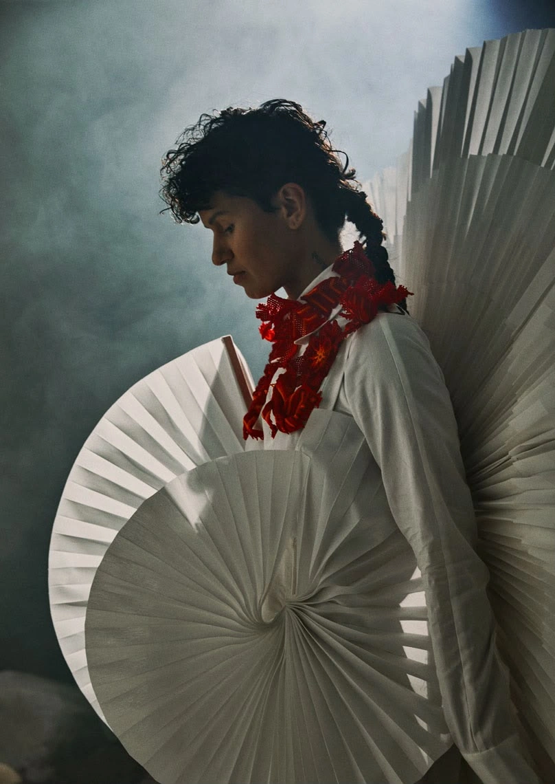 Binhe, photograph 11, photographed by Violaine Chapallaz: a model in profile wearing white sculptural palm forms and a red floral collar. Design assistance and product design by Storm Nijhuis for Zyanya Keizer.