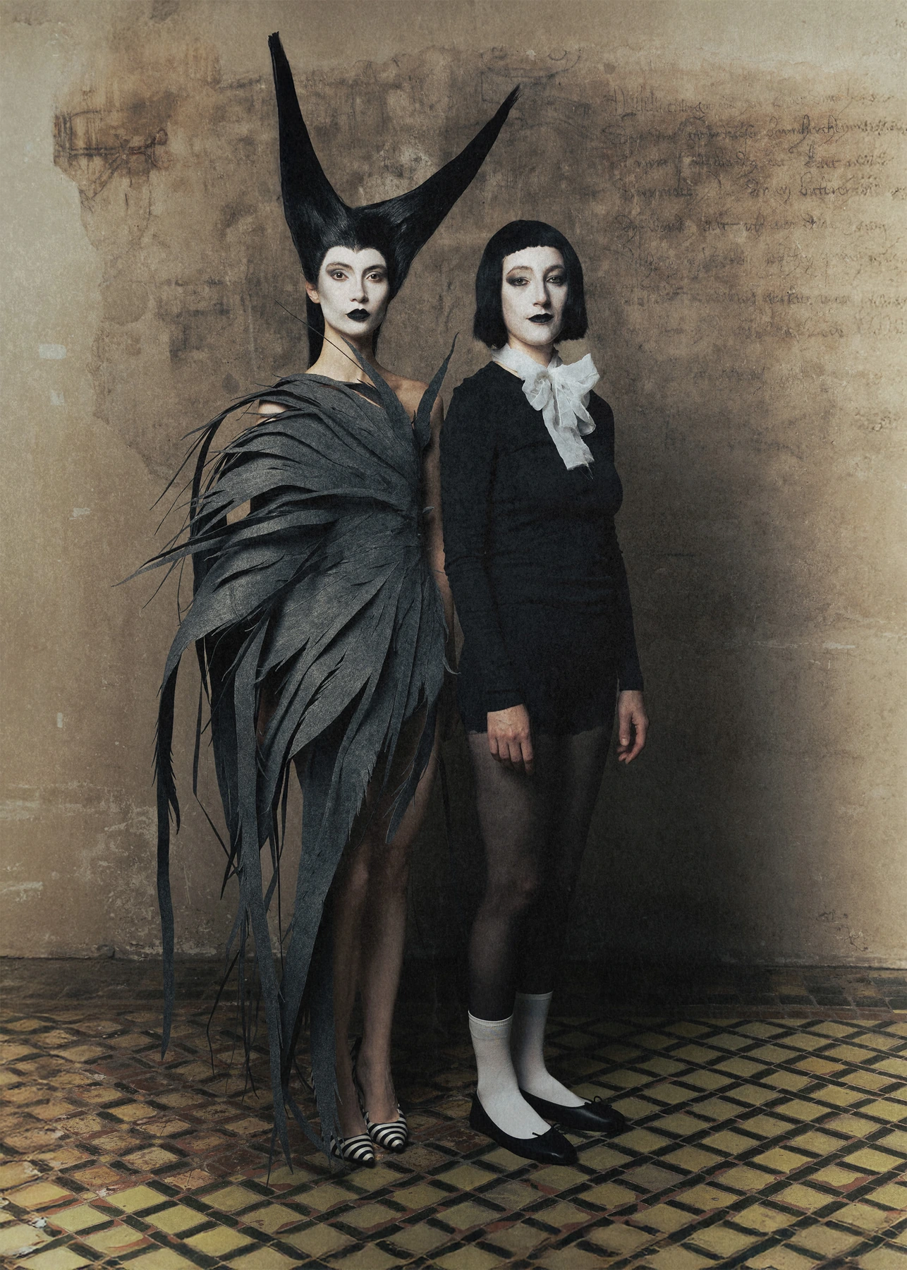 Two models in Hellion: a sculptural horned silhouette and a black tailored look with a white collar.